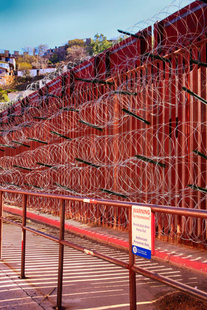The US-Mexican border wall with layers of razor wire at Nogales AZ The US-Mexican border wall with layers of razor wire at Nogales AZ nogales arizona stock pictures, royalty-free photos & images