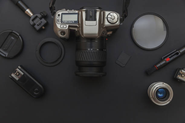 istock Photographer workplace with dslr camera system, camera cleaning kit, lens and camera accessory on dark black table background. Hobby travel photography concept. Flat lay top view copy space 1202126883