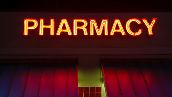 A neon sign over a pharmacy on a roof