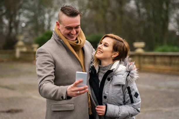 istock Young Couple Laughing at Something on Smartphone 1202128299