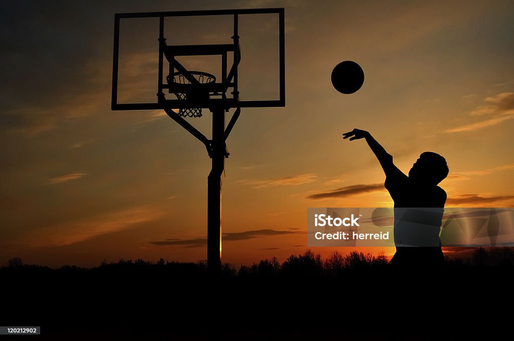 Backlit silhouette of a teen boy shooting a basketball Silhouette of Teen Boy Shooting a Basketball at Sunset, copy space Sunset Stock Photo