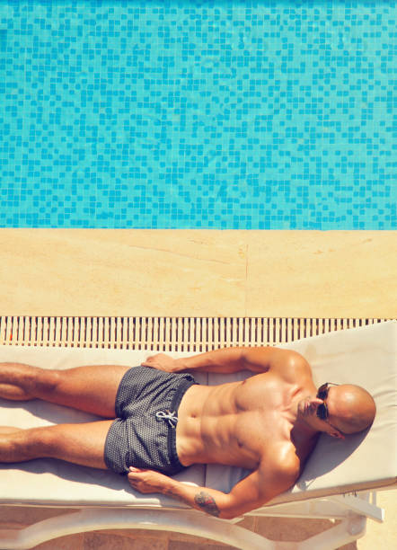 istock Man on a sun lounge by swimming pool 1202129070