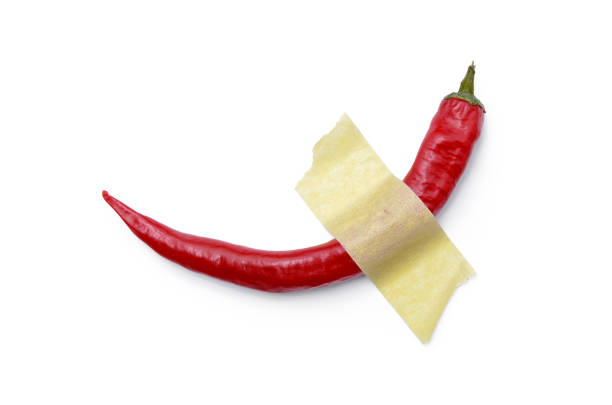istock Red, hot pepper glued with yellow tape to a white surface. Modern pop art 1202129312