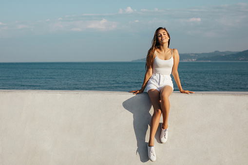 Beautiful girl sits on a background of the sea