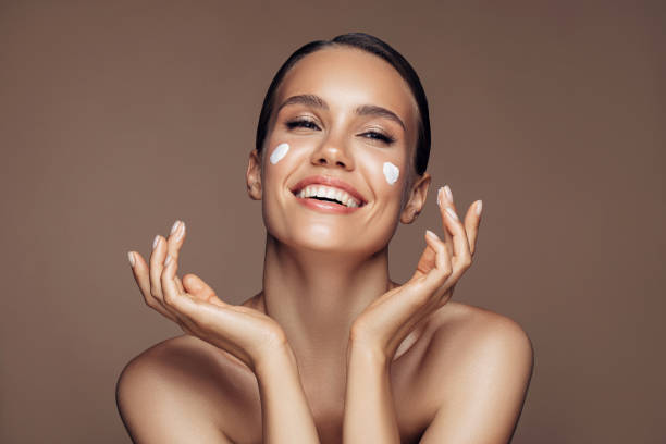 istock Beautiful woman applying cream on her face 1202131761