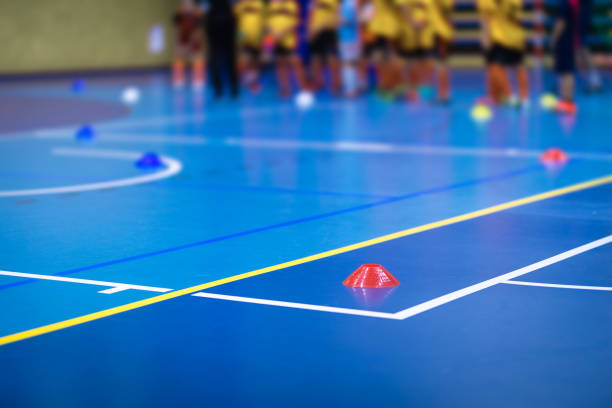Sports team on futsal training field. Indoor soccer training during the winter. Futsal training field with blue cones. Indoor football practice for children. Physical education unit of soccer equipo deportivo en campo de entrenamiento de fútbol sala. entrenamiento de fútbol sala durante el invierno. campo de entrenamiento de fútbol sala con conos azules. práctica de fútbol sala para niños. unidad de educación física del fútbol