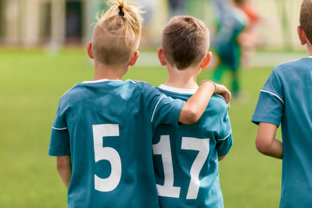 dwóch młodych chłopców jako kolegów z drużyny sportowej. przyjaźń w sporcie juniorskim. młodzi piłkarze spędzają razem czas na sobie - football child american football team zdjęcia i obrazy z banku zdjęć