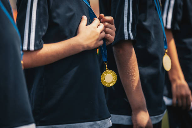 sports kids players with golden medals standing in a row during celebration. medals hanging around young sport players necks - soccer celebration success group of people imagens e fotografias de stock