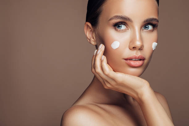 istock Beautiful woman applying cream on her face 1202131840