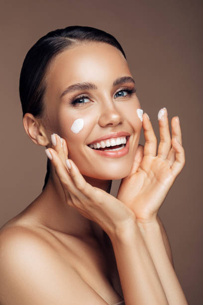 istock Beautiful woman applying cream on her face 1202132382