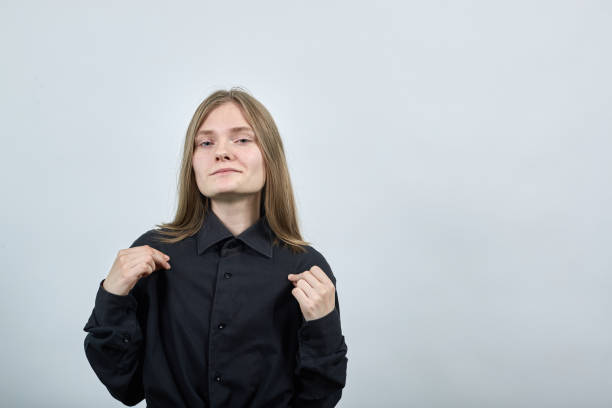 istock Attractive young woman on gray wall pulls shirt with fingers, looking at camera. 1202132760