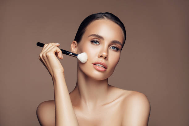 istock Beautiful young woman applying foundation powder 1202133917