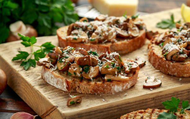 tostadas de champiñones a la brasa con perejil, limón y queso parmesano sobre tabla de madera. alimentos veganos saludables - brushetta fotografías e imágenes de stock