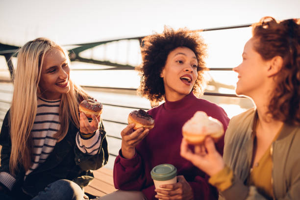 istock Girls sitting and eating donuts 1202136255