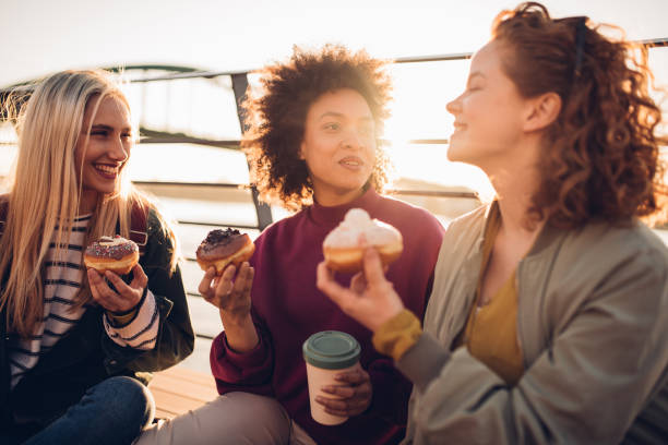 istock Girls sitting and eating donuts 1202136257