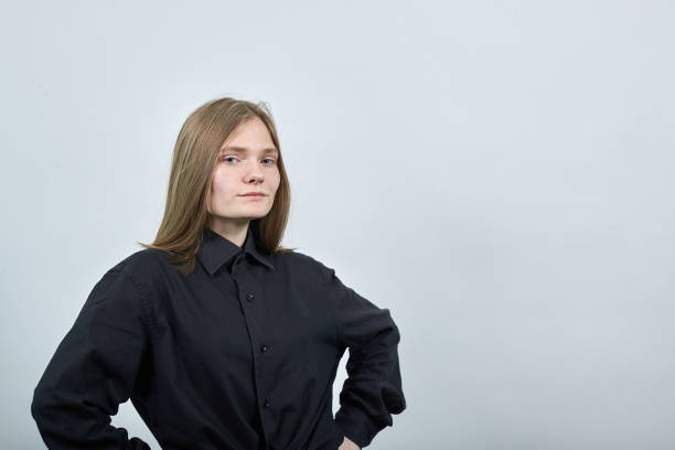 istock Serious attractive woman on gray wall keeping hands on belt, looking at camera. 1202138744