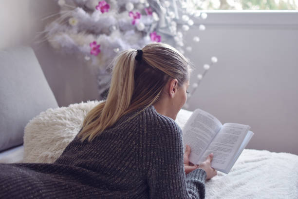 istock Relaxed woman reading a book in her bed 1202140368