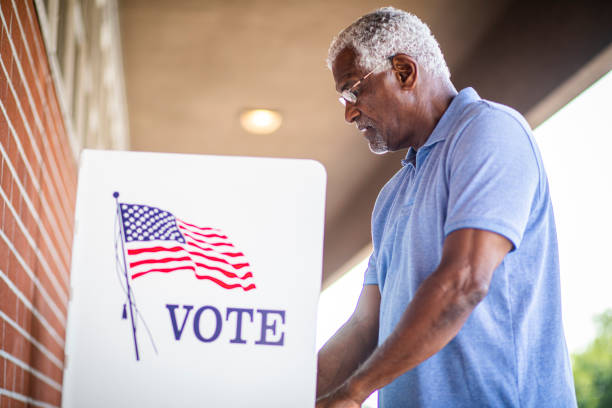 Senior Black Man Voting at Booth A senior black man voting at a voting booth ballot box photos stock pictures, royalty-free photos & images