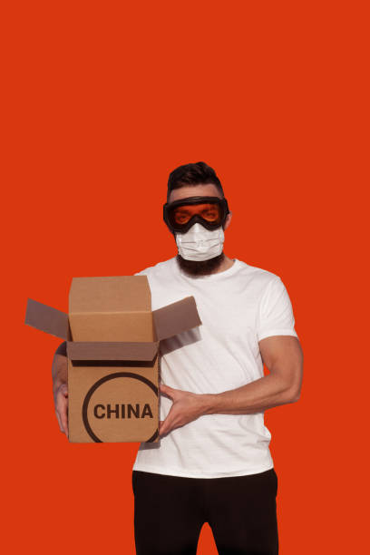 istock Man in protective goggles and surgical mask unpacking cardboard 1202147824