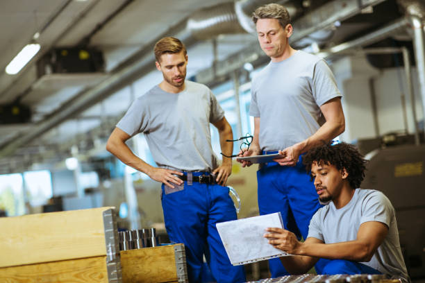 istock Senior male inspector doing quality control with manual worker looking at document and examining metal tube 1202148002