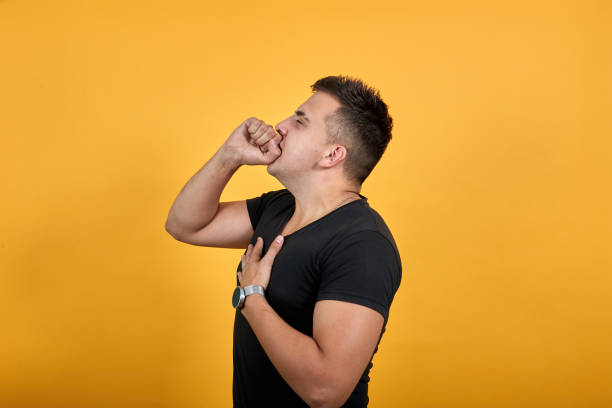 istock Sickness young man covered mouth with hand, cough, keeping hand on chest. 1202149722