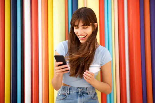 Photo of happy young woman with long hair looking at mobile phone against colorful background