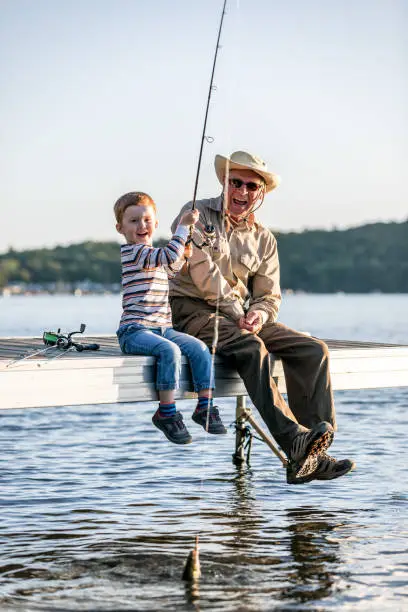 Photo of Grandfather and Grandson Fishing At Sunset in Summer