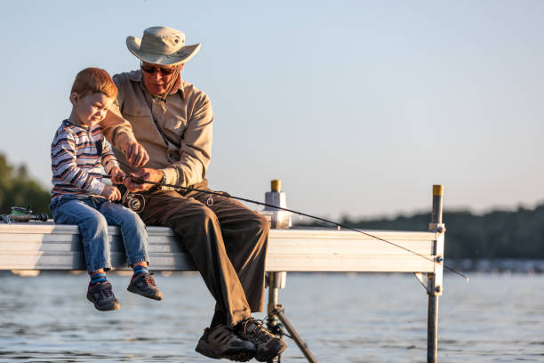 avô e neto pescando ao pôr do sol no verão - fishing active seniors family senior adult - fotografias e filmes do acervo