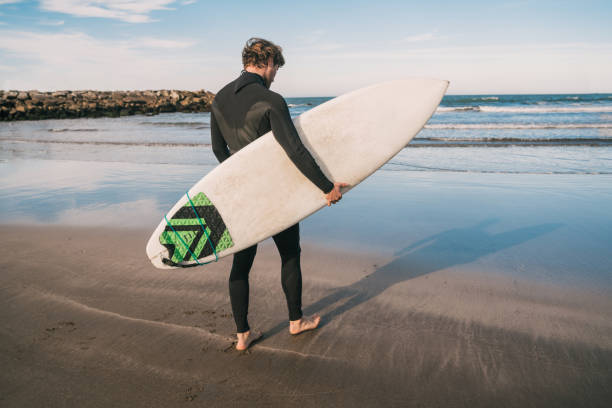 istock Surfer entering into the water with his surfboard. 1202154526