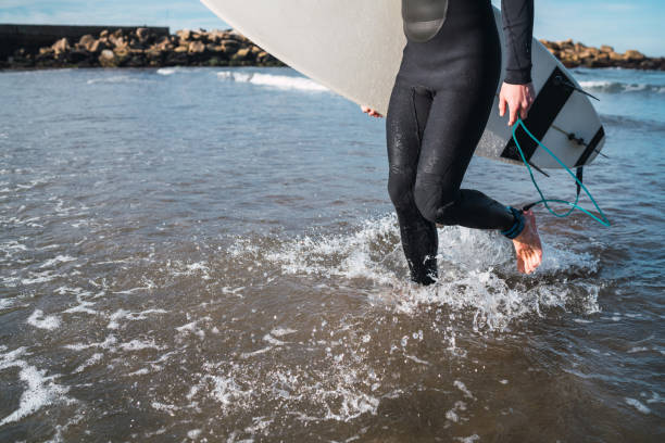 istock Surfer entering into the water with his surfboard. 1202154559