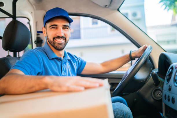 istock Delivery man driving van with cardboard boxes on seat. 1202154592