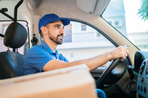 istock Delivery man driving van with cardboard boxes on seat. 1202154646