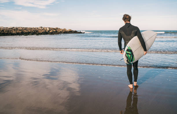 istock Surfer entering into the water with his surfboard. 1202154799