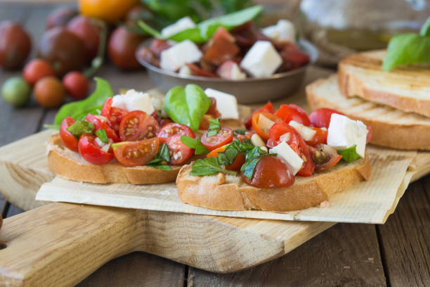 istock Bruschetta with tomatoes, mozzarella cheese and basil on a cutting board. Traditional italian appetizer or snack, antipasto. Top view with copy space. Flat lay 1202156055