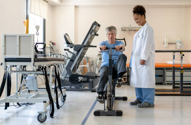 istock Friendly black female therapist instructing male senior patient on static bicycle during physical therapy 1202157423