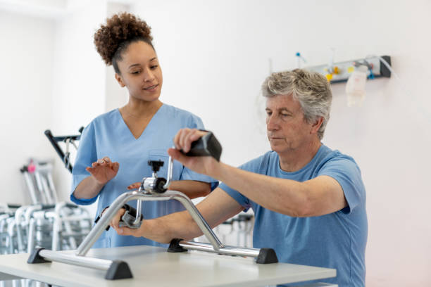 istock Black female therapist instructing senior patient how to exercise his arms on machine during physical therapy 1202157451