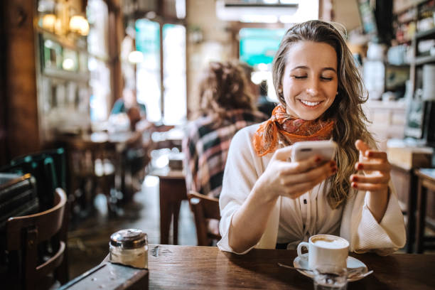 istock Young woman using mobile phone in coffee shop 1202168080