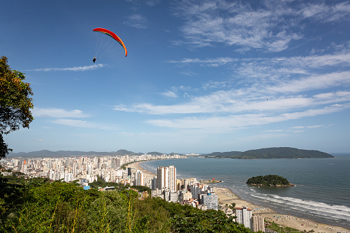Aerial view of the beach in the city of Santos, Brazil,  and in the background the city of Guaruja.On the left, a paraglider enjoying the view.