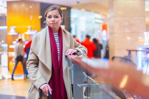 at the mall lifestyle fashion portrait of stunning brunette girl. walking on at the mall. going shopping. wearing stylish white fitted coat, red neckscarf, black umbrella cane. business woman - neckscarf imagens e fotografias de stock