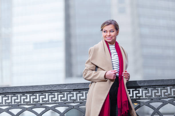 outdoors lifestyle fashion portrait of stunning brunette girl. walking on the city street. going shopping. wearing stylish white fitted coat, red neckscarf, black umbrella cane. business woman - neckscarf imagens e fotografias de stock