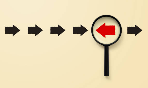 Magnifying glass searching for red arrow facing the opposite direction black arrows, unique, think different, individual and standing out from the crowd concept