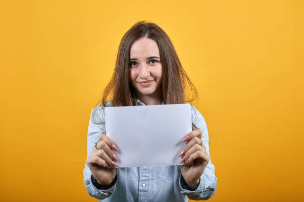 Cheerful attractive woman keeping white paper, smiling, looking at camera.