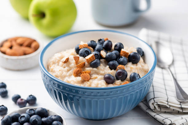 ciotola di porridge di farina d'avena con mirtilli e mandorle - oat wheat oatmeal cereal plant foto e immagini stock