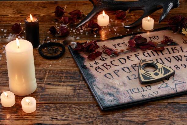 istock Mystic ritual with Ouija and candles. Devil's board concept, black magic or fortune telling rite with occult and esoteric symbols. 1202188967