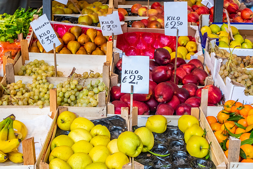 A beautiful young woman choosing peaches at a farmer's food market stall. For a more sustainable world, the purchase is carried in a canvas bag.