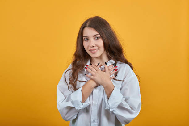 istock Cheerful young woman keeping hands on chest, looking at camera, smile 1202197086