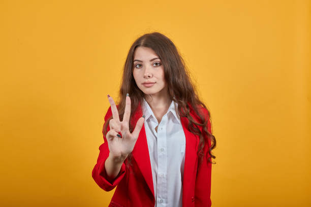 istock Cheerful young woman showing three fingers, looking at camera 1202205223