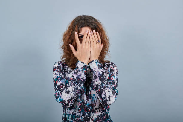 istock Charming young woman covered face with hands, looking through it 1202209479