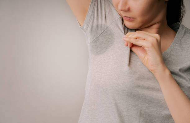 atractiva mujer vergonzosa en su mancha de sudor en su camiseta gris. mujer asiática olor desagradable del sudor en la axila con fondo gris.healthcare e hiperhidrosis o conceptos de sudoración excesiva - deodorant women hygiene body care fotografías e imágenes de stock