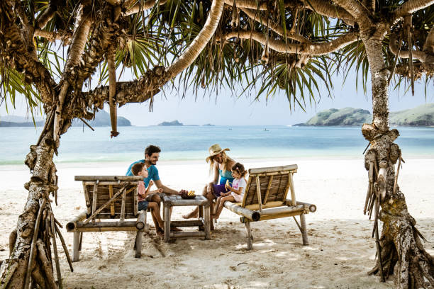 istock Happy family talking while relaxing on deck chairs at the beach. 1202211586